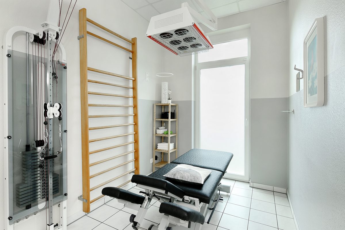 Behandlungsraum mit Therapieliege, Seilzug, Sprossenwand und W&auml;rmelampe
